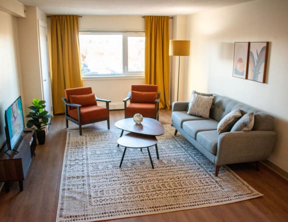 a living room with a gray couch and two orange chairs