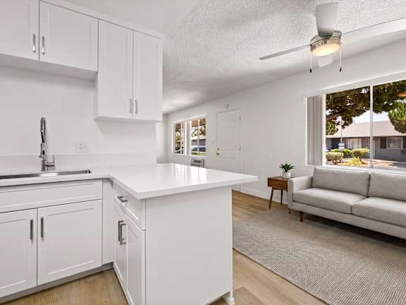 A kitchen with a table and chairs in front of a fridge and cabinets.