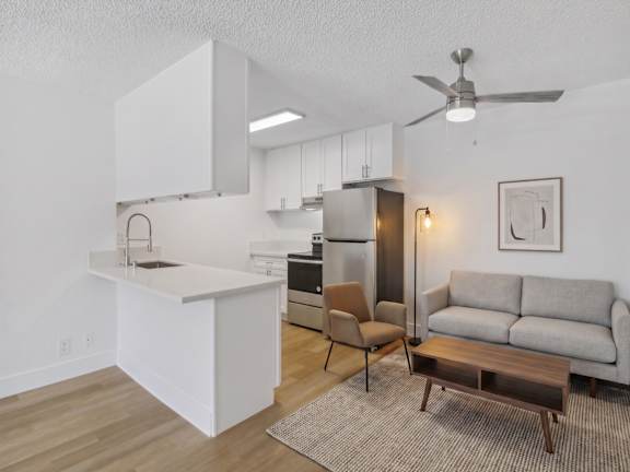 A kitchen with a table and chairs in front of a fridge and cabinets.