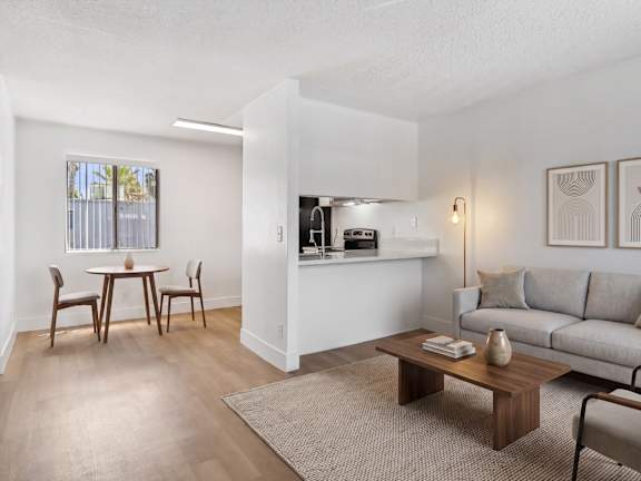 A kitchen with a table and chairs in front of a fridge and cabinets.