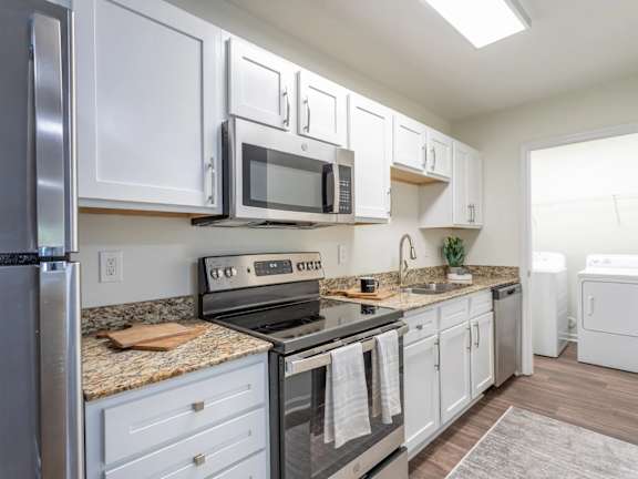 A kitchen with white cabinets and a granite countertop.