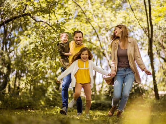 Family Running Through Woods Together Smiling