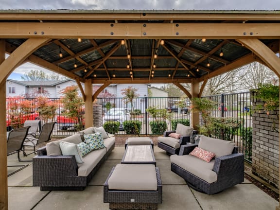 an outdoor patio with couches and tables under a wooden pergola