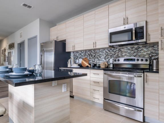 Reveal Heathrow apartments kitchen with custom cabinetry and quartz countertops