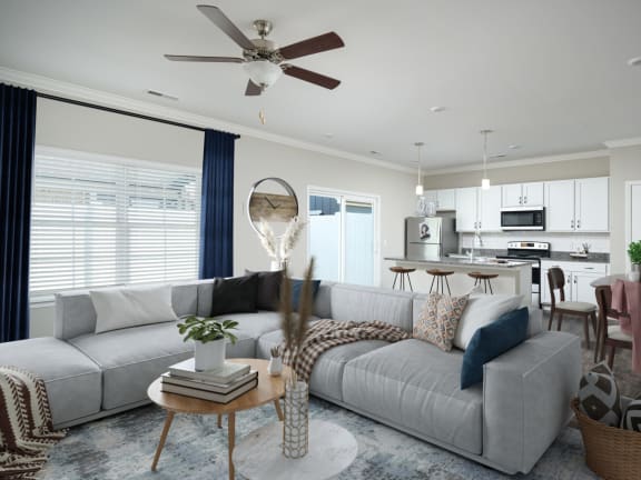 a living room with a gray couch and a white and blue kitchen in the background