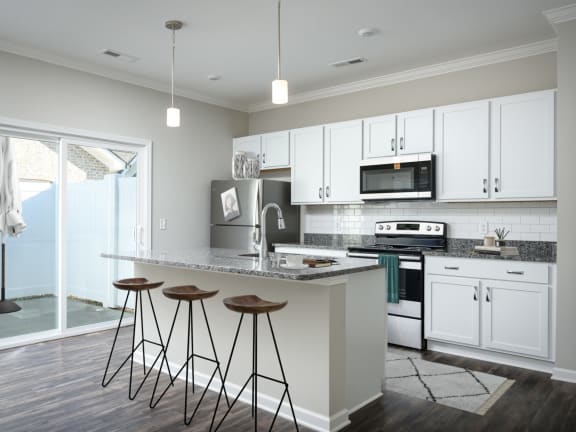 a kitchen with white cabinets and a large island with three stools