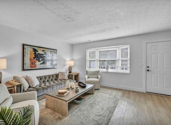 A living room with a grey couch, a coffee table, and a painting on the wall.