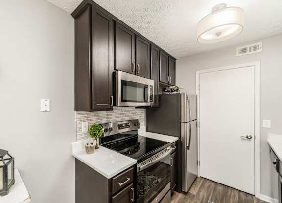 A kitchen with dark brown cabinets and a black stove top oven.