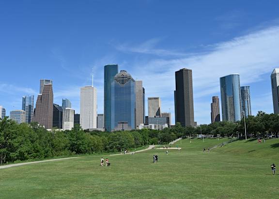 A city skyline with tall buildings and a green park in the foreground at Whitney at the Heights, Houston