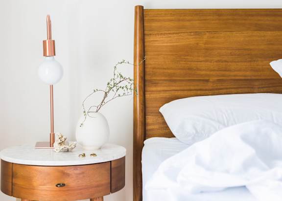 a bed with a wooden headboard and a table with a lamp