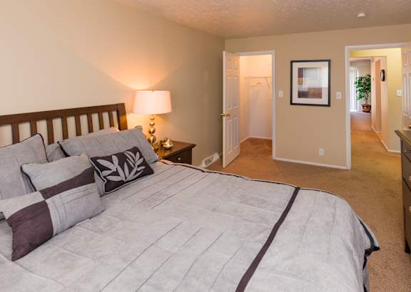 A bedroom with a large bed and a lamp on a side table.
