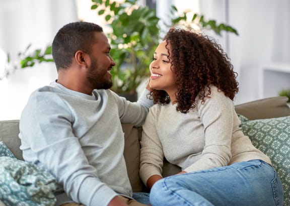 a man and woman sitting on a couch laughing