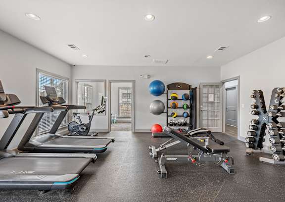 A spacious home gym with treadmills, exercise balls, and dumbbells.