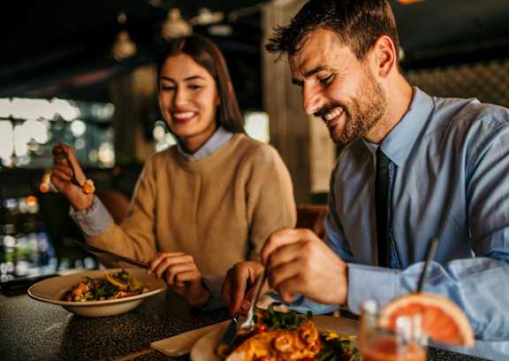 Man and Woman Smiling while Eating Food Together
