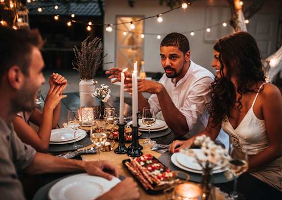 Friends Smiling and Talking while Having Dinner and Drinks Outside