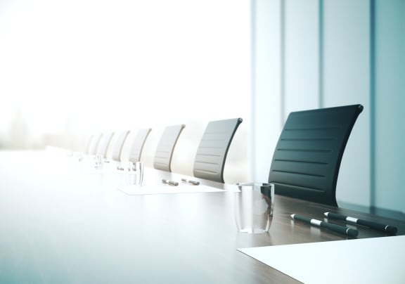 a boardroom table with chairs and a glass of water