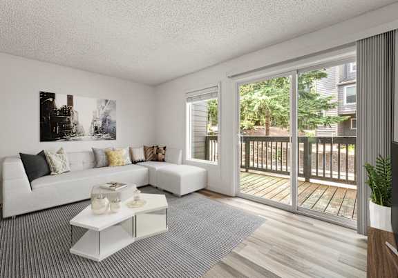 A white couch with pillows sits in a room with a coffee table in front of it.