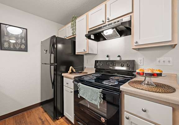 A kitchen with white cabinets and black appliances at Clackamas Trails Apartments, Oregon, 97222