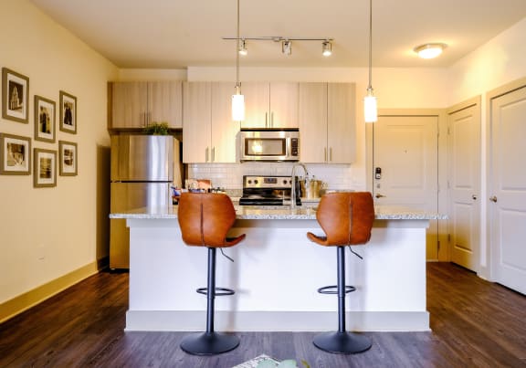 a photo of a kitchen island with barstools and kitchen in the background
