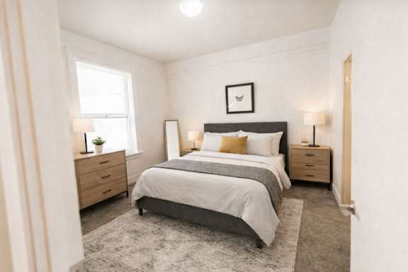 A bedroom with a large bed, two nightstands, and a window.