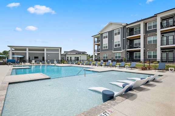 A large swimming pool in front of apartment buildings.