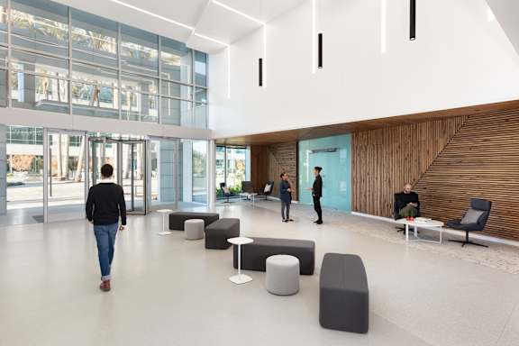 A man is walking through a spacious lobby with people standing in the background.