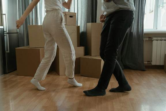 Two people dancing in a room with cardboard boxes.