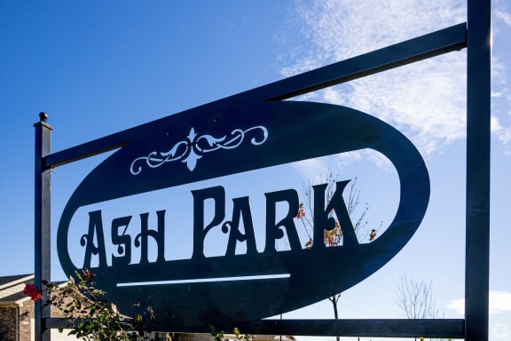 a sign for ash park against a blue sky