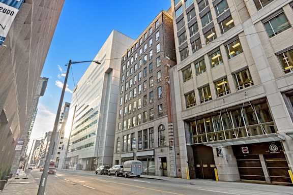 A street view of a city with a large building on the right and a truck parked in front of a garage door.