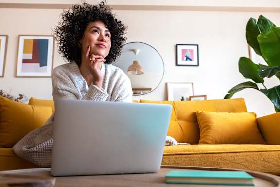 A person with curly hair is sitting in front of a laptop.