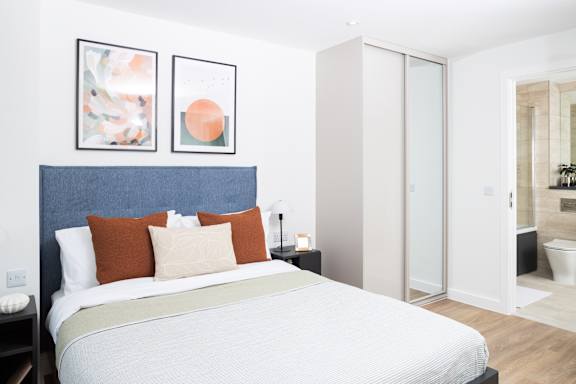 A bedroom with a bed, two pillows, and two pictures on the wall.