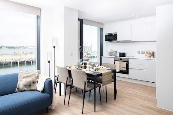 A modern kitchen with a dining table set for two.