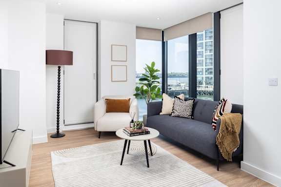 A living room with a grey couch, a coffee table, and a large window.