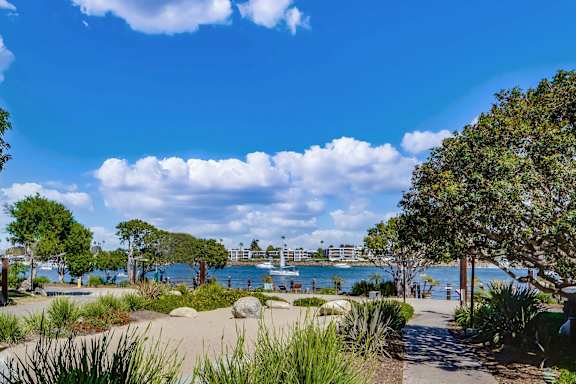 A pathway leads through a grassy area to a body of water with boats.