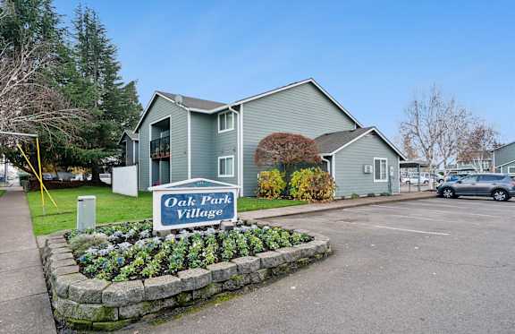 A sign that says Oak Park Village in front of some houses.