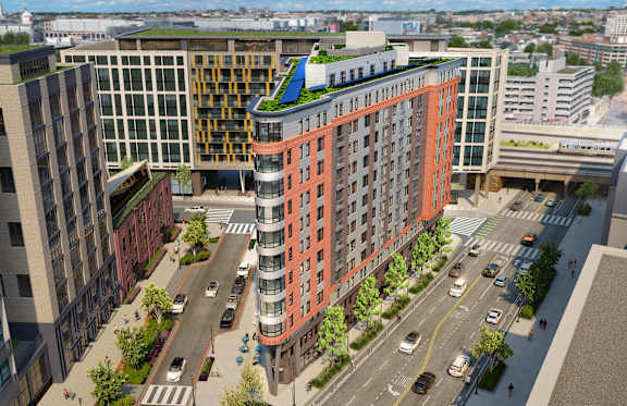 A modern building with a green roof is situated on a busy street.