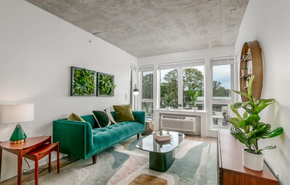a living room with a green couch and a large window