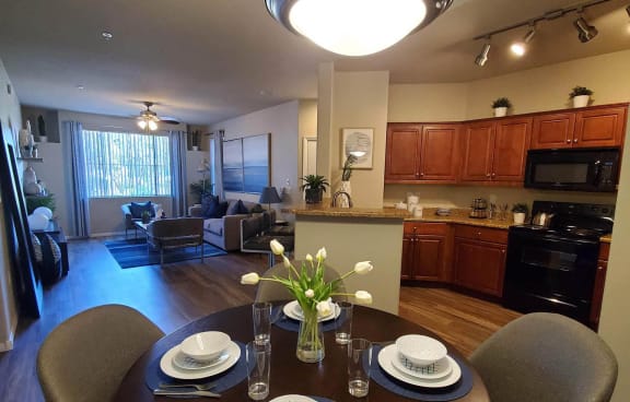 a dining room and living room area with a kitchen in the background