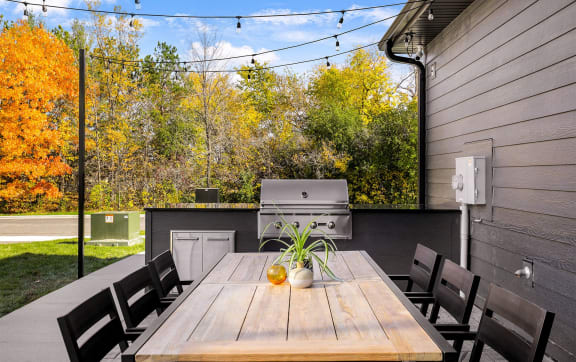 a patio with a table and chairs and a grill