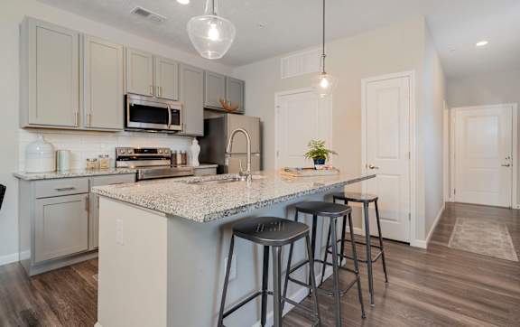 A kitchen with a granite countertop and bar stools.