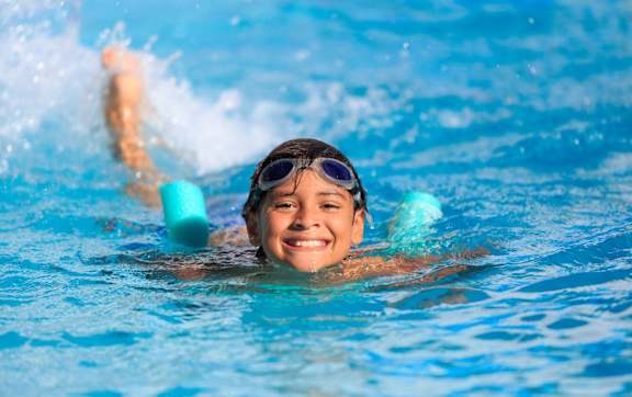 A person swimming in a pool with goggles on.