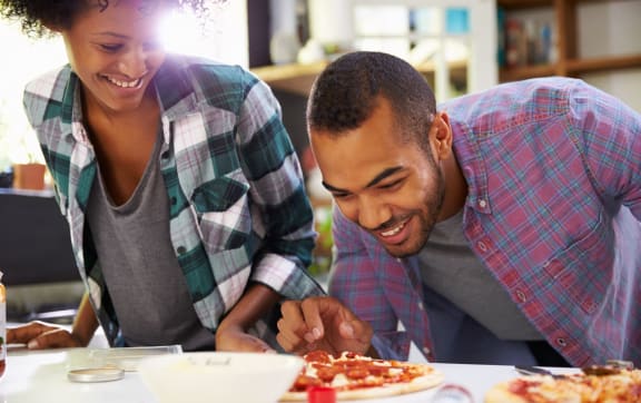 Man and Woman Smiling while Making Pizza Together