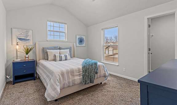 A bedroom with a bed, nightstand, and window.