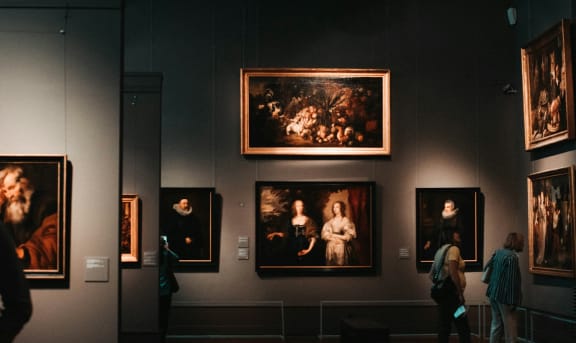 people looking at paintings in a gallery at the museum
