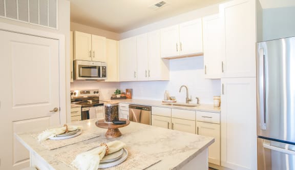 a kitchen with white cabinets and a marble counter top