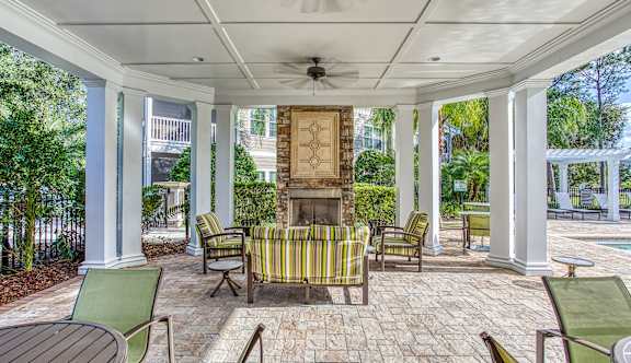 A covered patio with a fireplace and chairs.