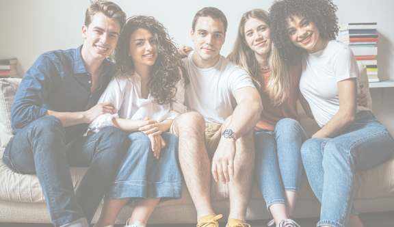 A group of people are sitting around a table taking a selfie.