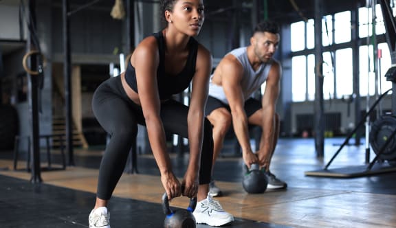 a man and woman lifting weights in a gym