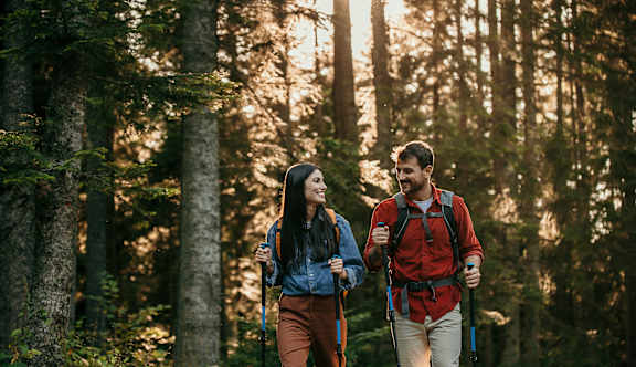 A man and a woman are hiking in a forest.