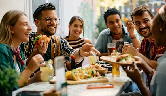 A group of people are sitting around a table taking a selfie.